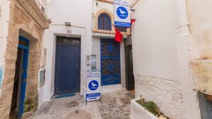 A narrow alleyway with a blue door and a signboard. - Riad Aylal (Essaouira)
