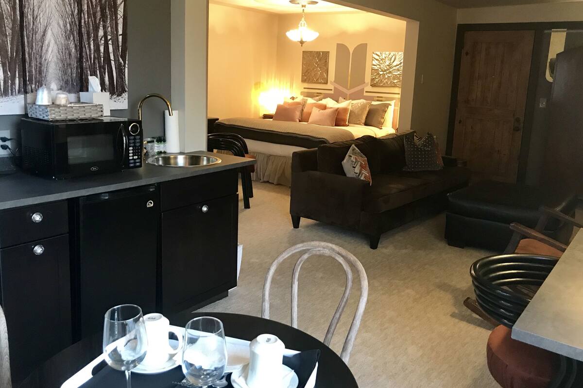 A compact living space with a kitchenette, a dining area, and a cozy seating area with a sofa and ottoman.
