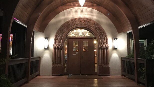 An arched entrance with a wooden floor, a double door, and two wall-mounted lights. - Colter's Lodge (Afton)