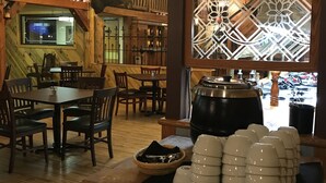 A rustic dining area with wooden furniture, a large decorative window, and a coffee station. - Colter's Lodge (Afton)