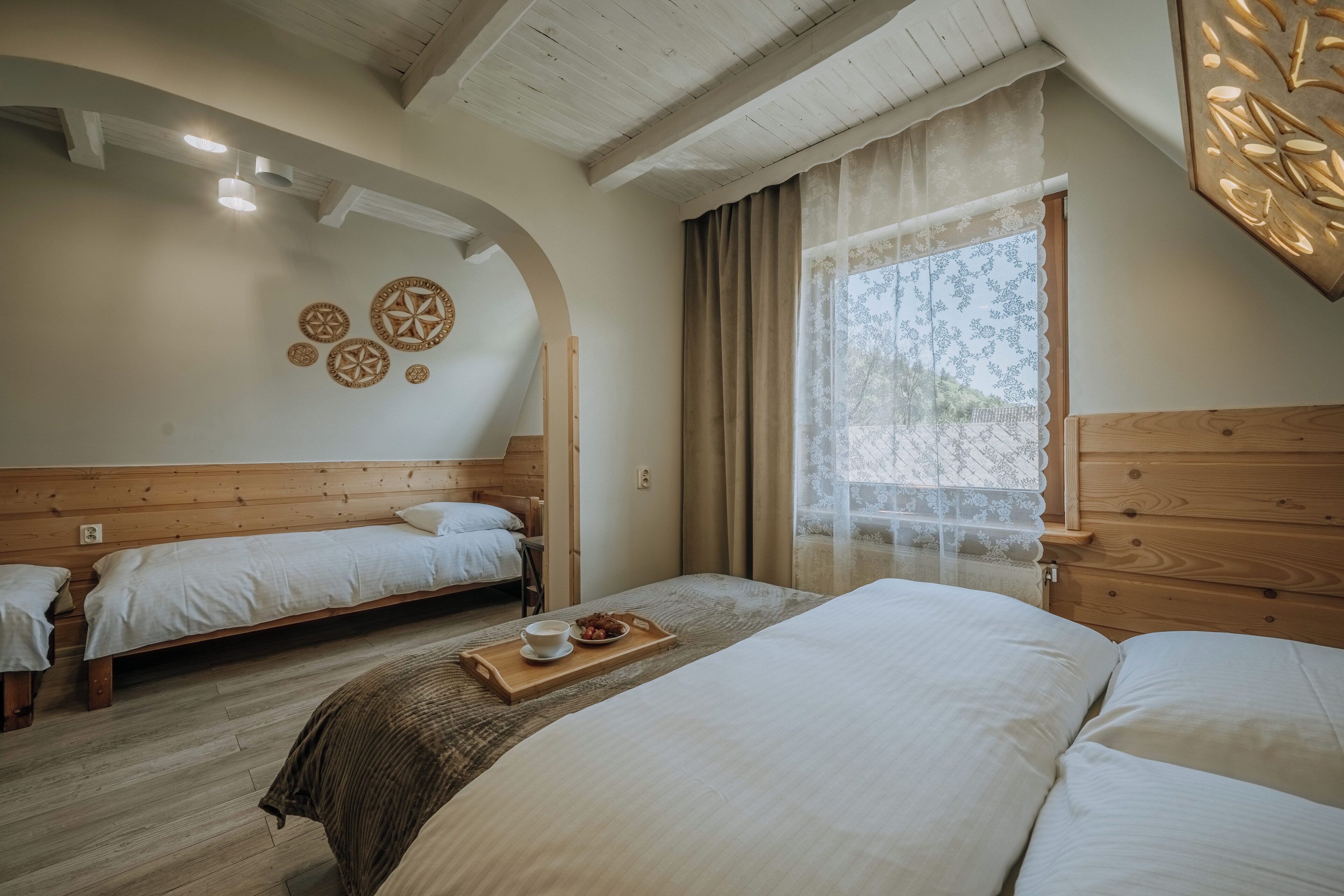 Een kamer met twee bedden, een houten plafond en een raam met gordijnen.