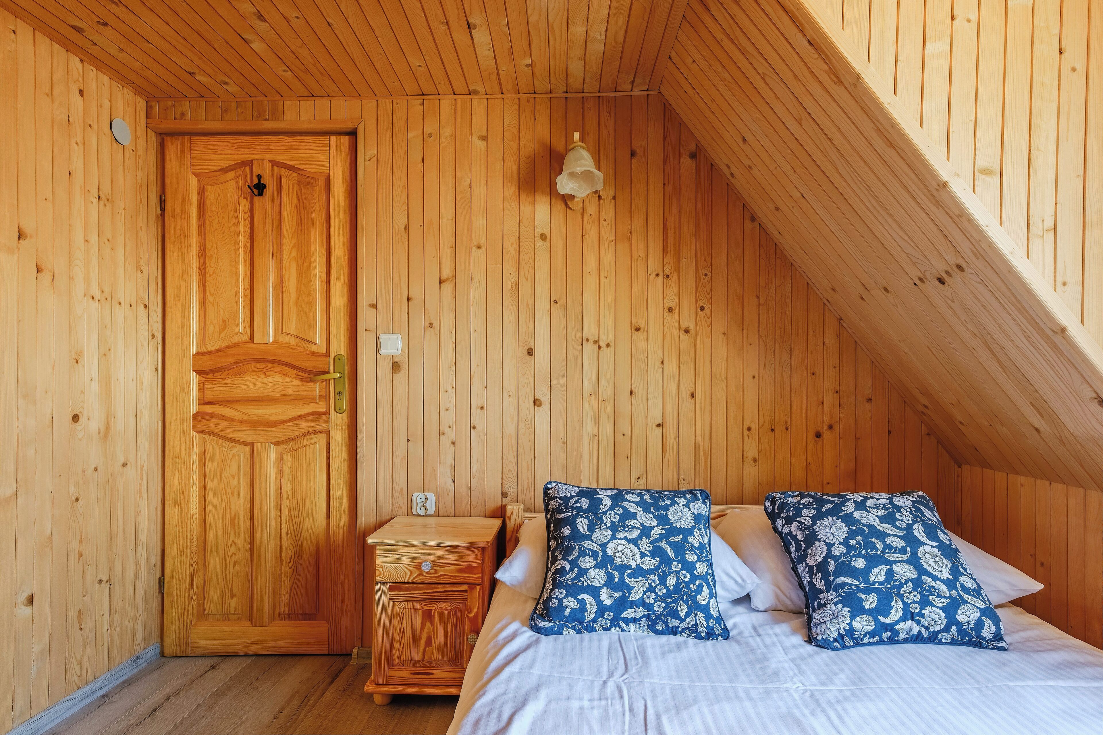Una habitación de madera con una cama, una mesita de noche y una puerta.