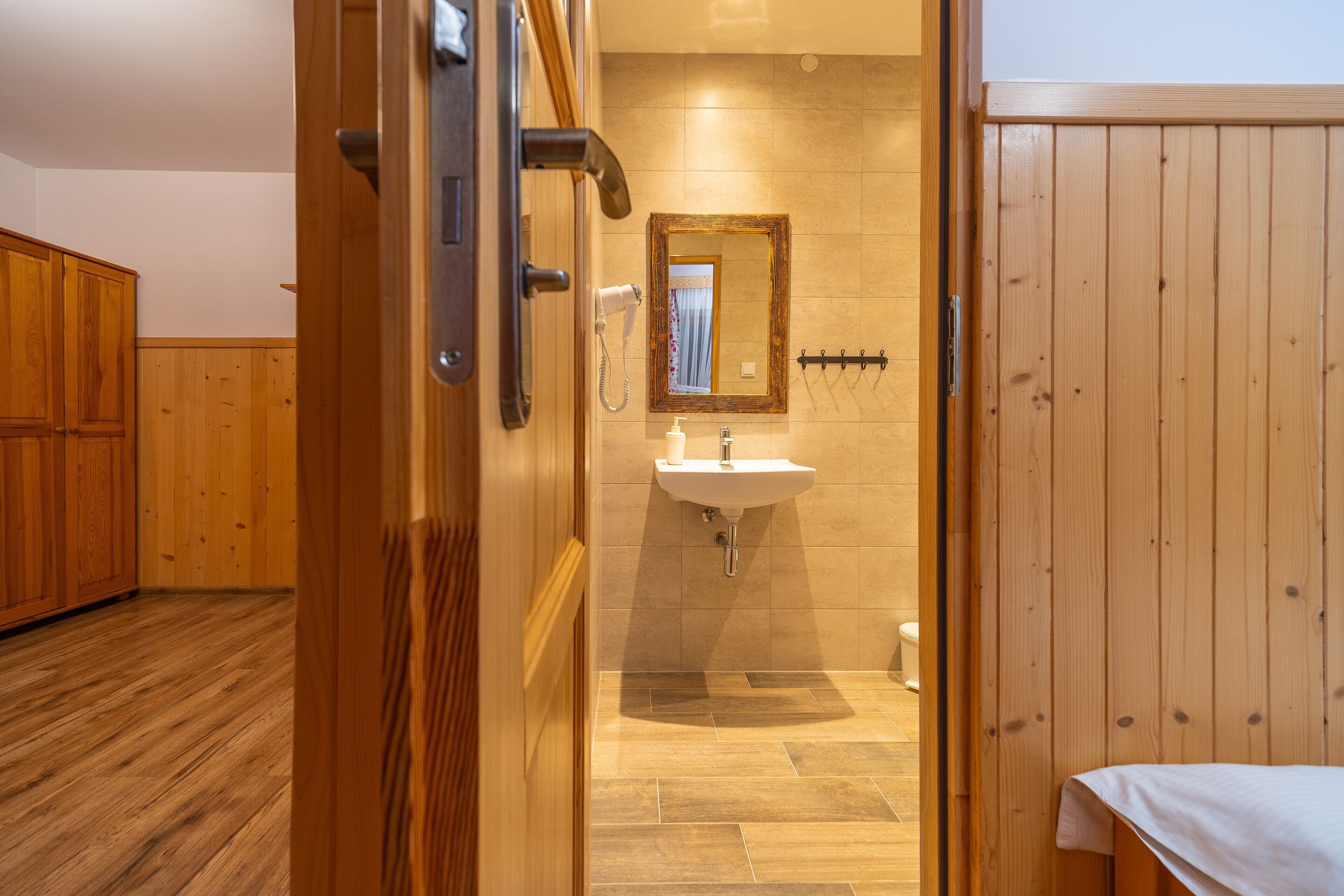 A wooden-floored bathroom with a sink, mirror, and towel rack.