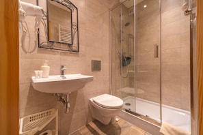Un baño moderno con ducha de vidrio, un lavamanos blanco y un inodoro.