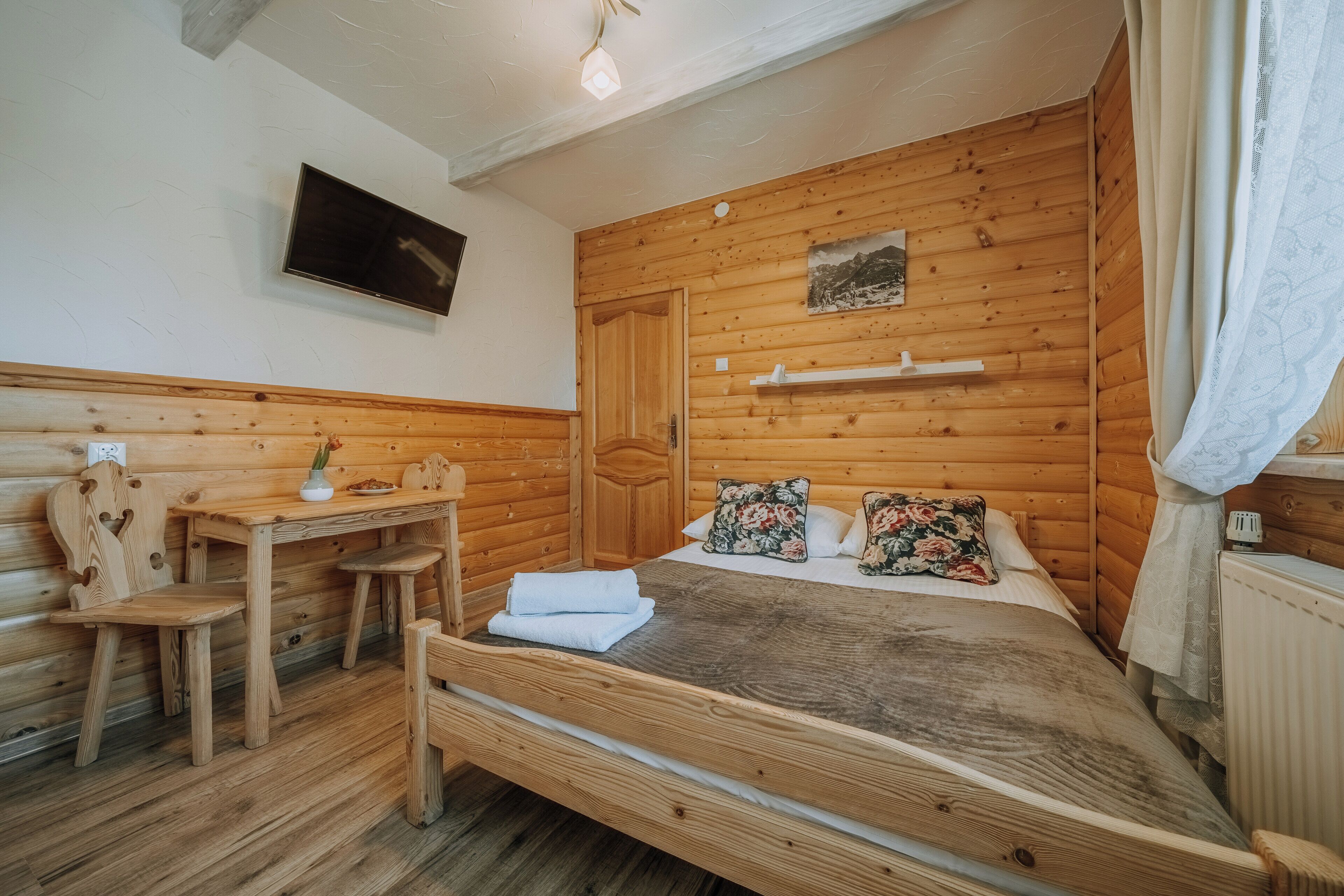 A wooden cabin bedroom with a bed, a desk, and a chair.