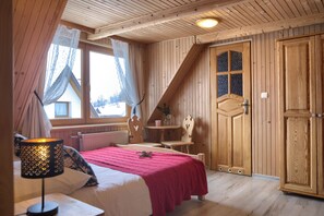 A wooden room with a bed, a table, and a door.