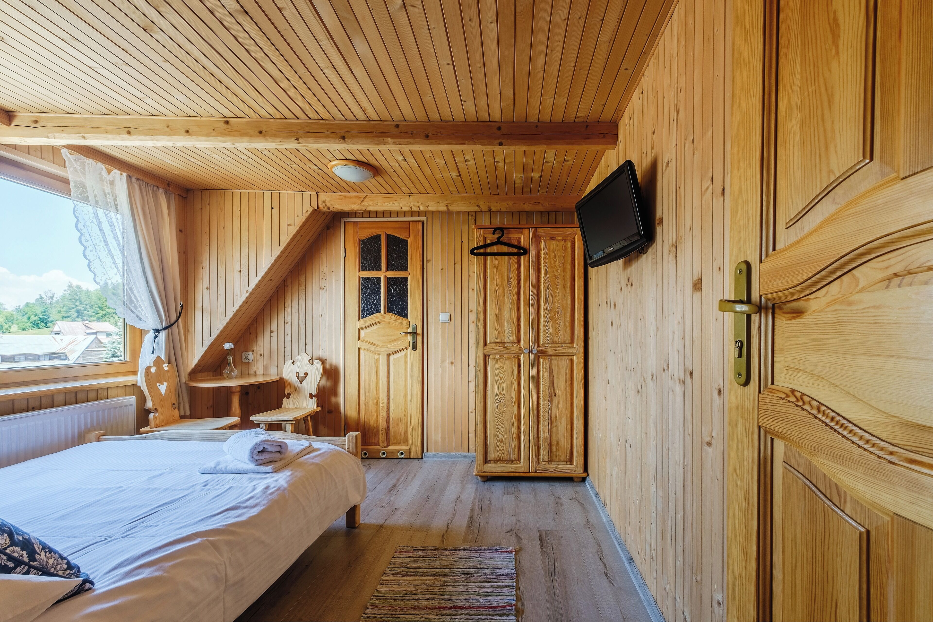 A wooden room with a bed, a table, and a chair.