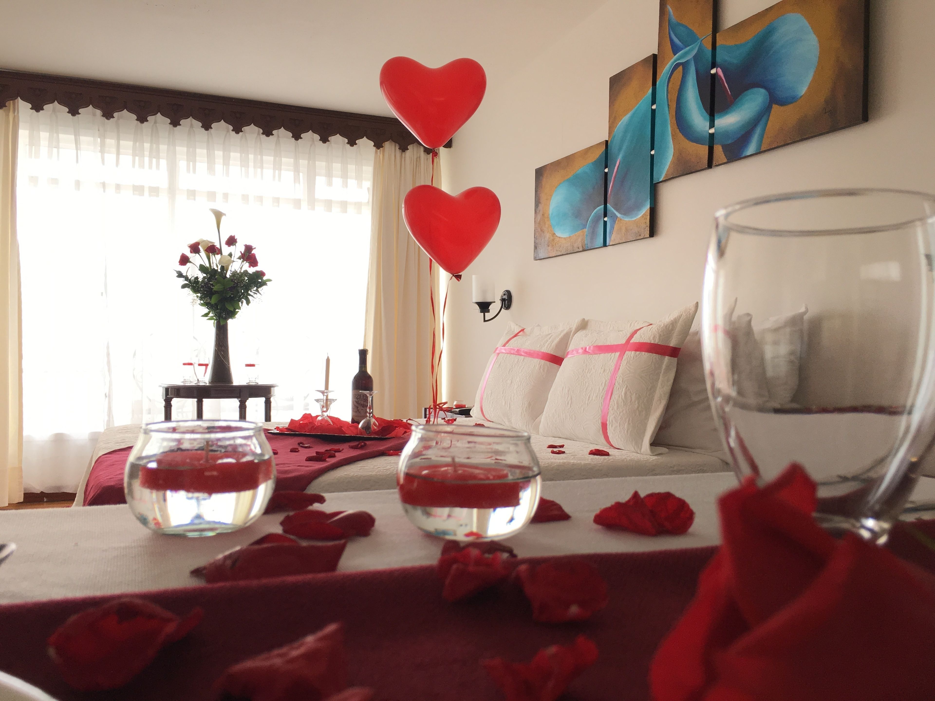 Una habitación acogedora con sofá, una mesa de vidrio con pétalos de rosa, un jarrón con flores y un cuadro en la pared.