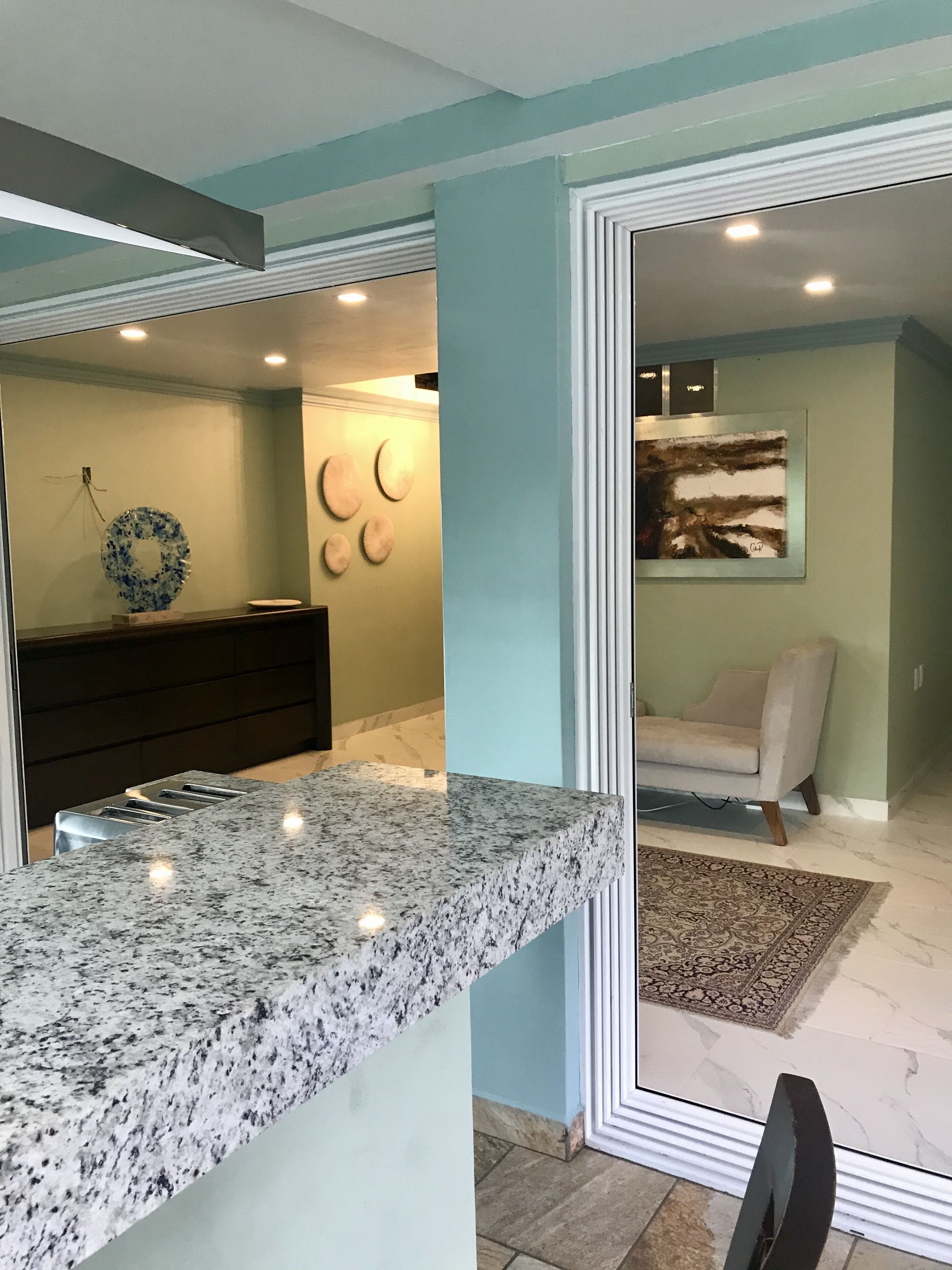 A modern kitchen with granite countertops, a dark wooden cabinet, and a decorative wall with circular art pieces.
