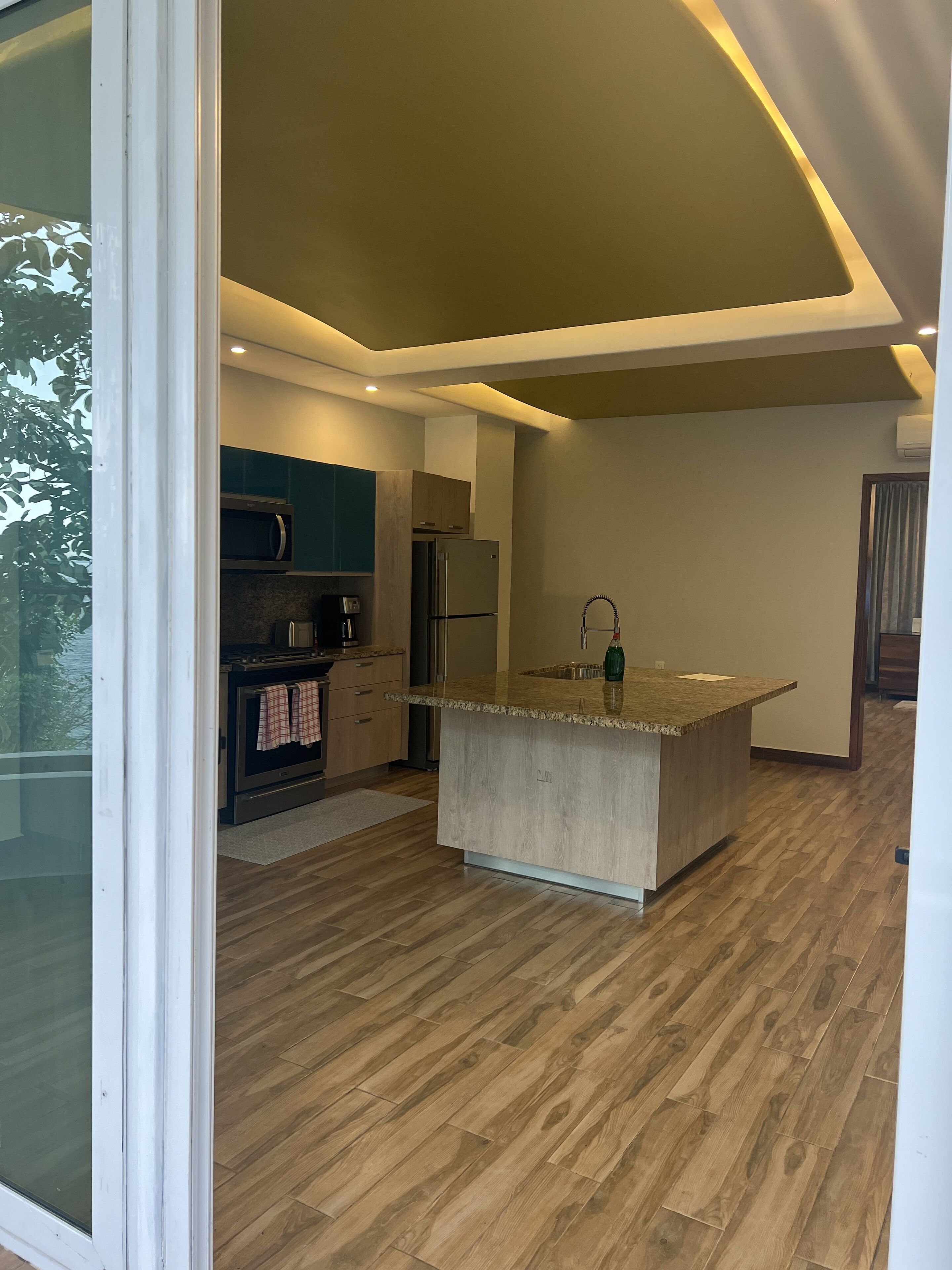 A modern kitchen with a central island, built-in appliances, and a wooden floor.
