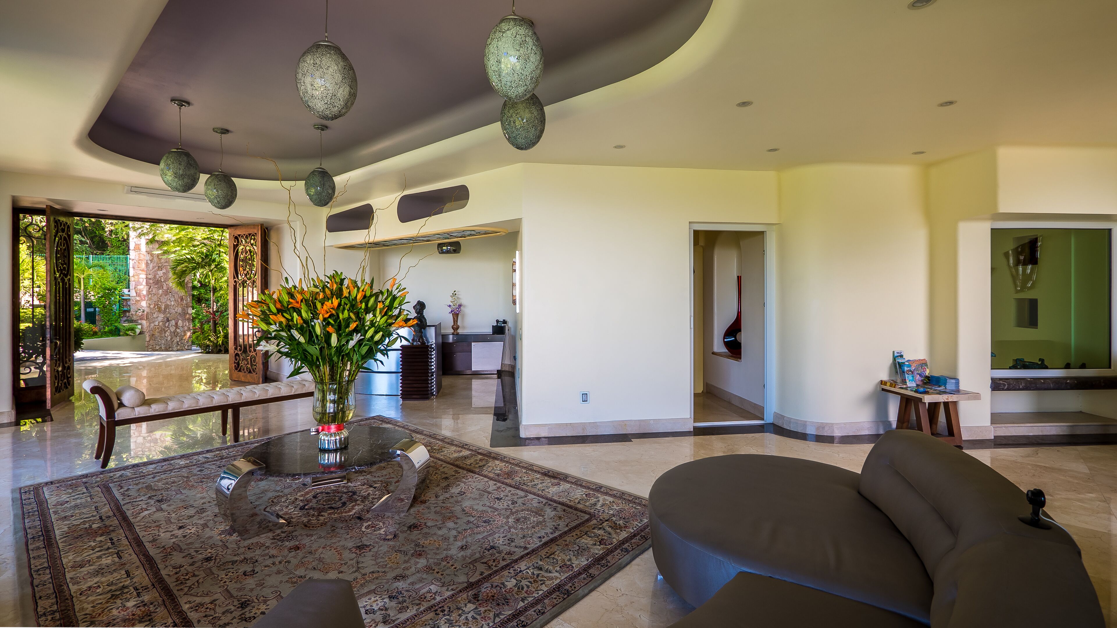 A spacious living room with a modern sofa, a glass coffee table, and a decorative vase with flowers.