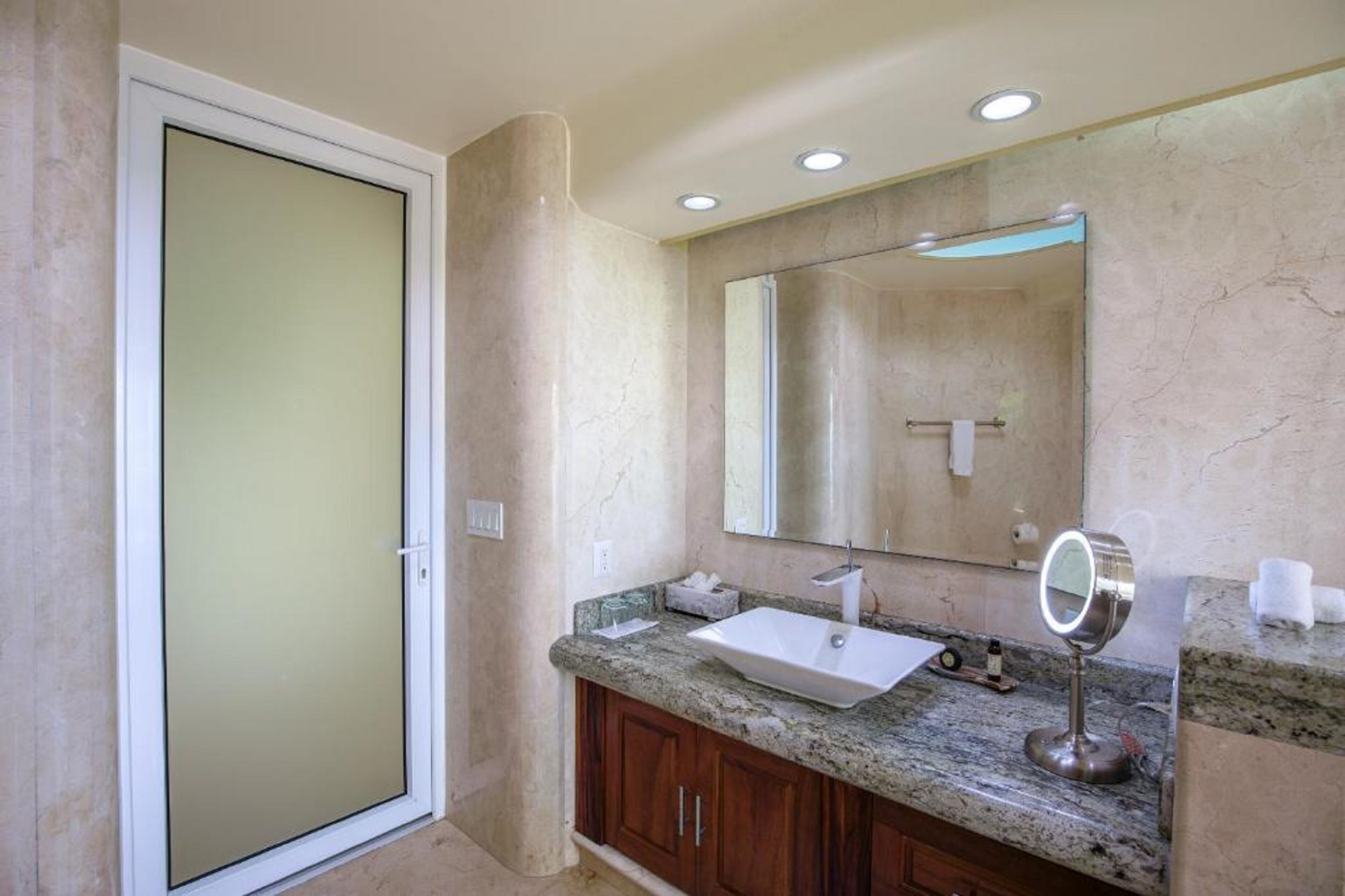 A bathroom with a large mirror, a sink, and a vanity with cabinets.