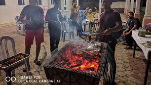 An outdoor event with a grill, people gathered around, and a banner with contact information. - Marang Village Resort & Spa (Marang)