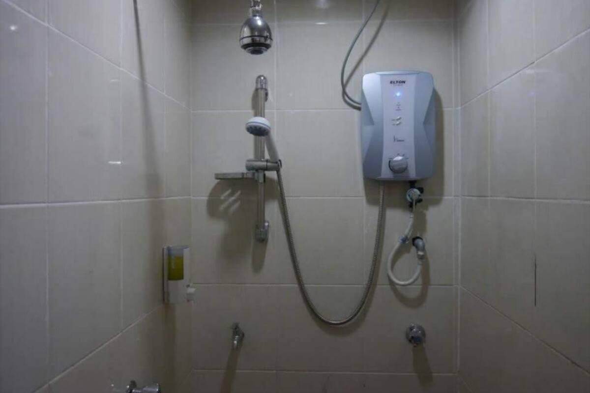 Ein Badezimmer mit Duschkabine, Handbrause und Bedienfeld.