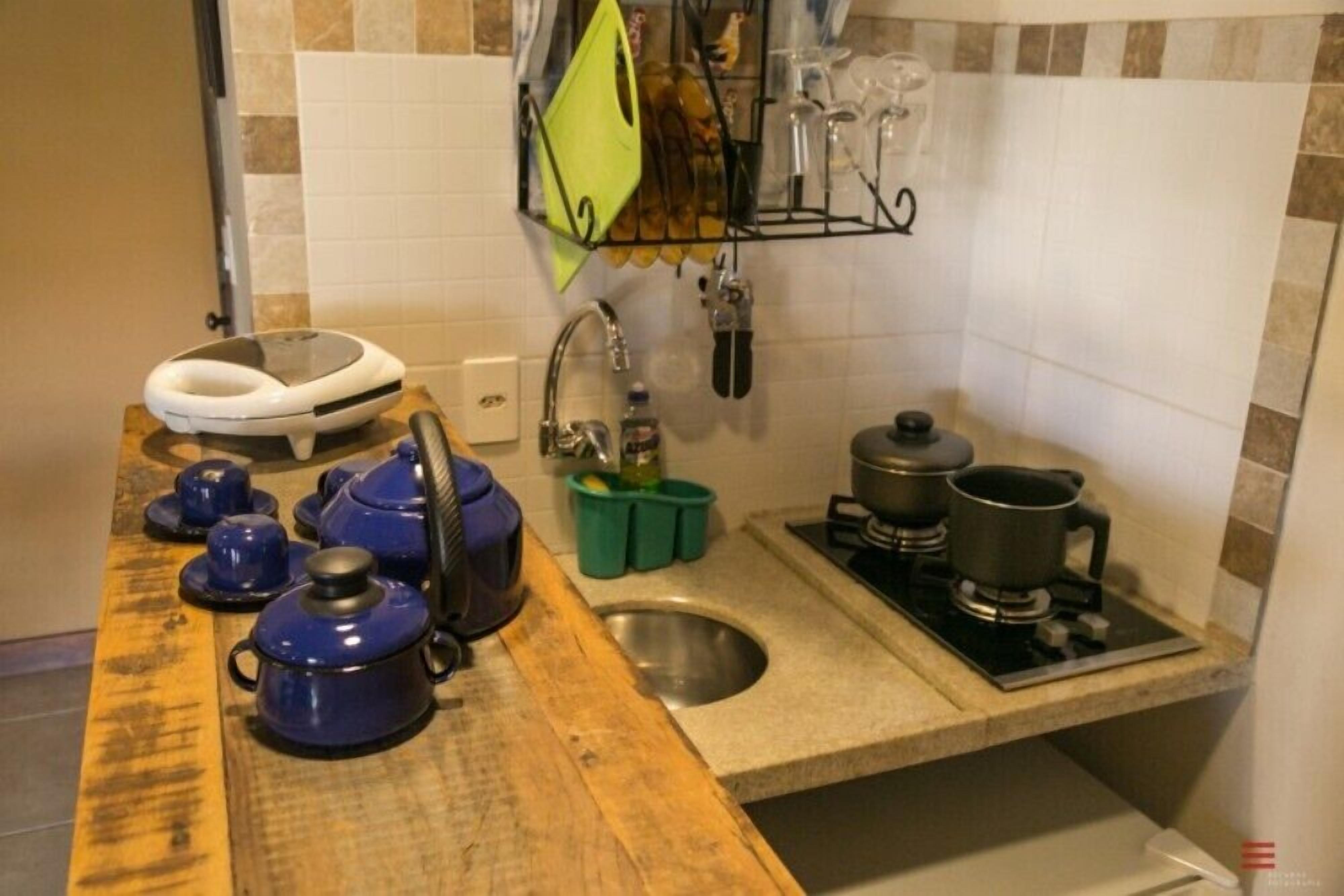 A kitchen with a wooden countertop, a sink, and a stove. There are blue pots and a white appliance on the counter.