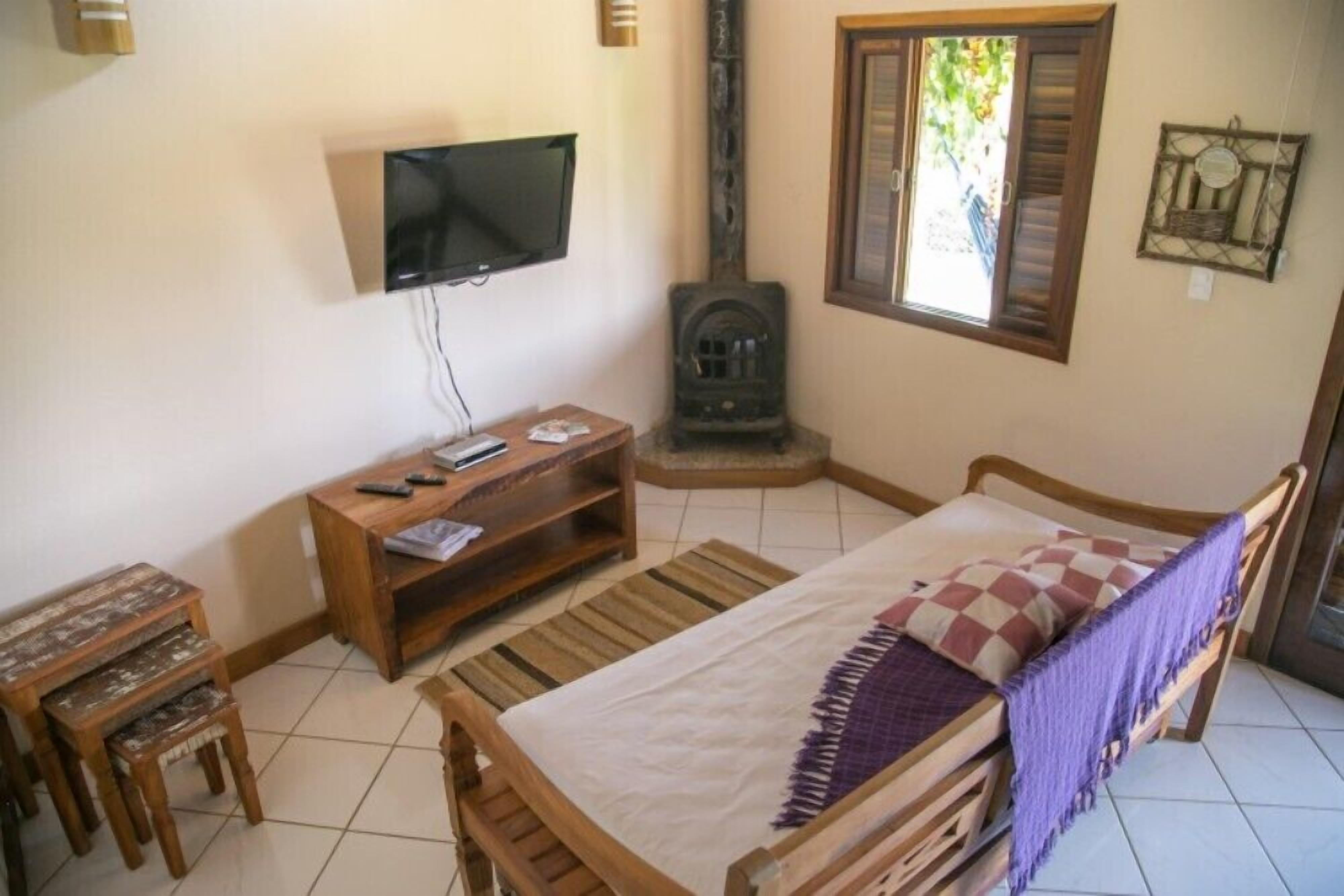 A cozy room with a bed, a wooden desk, a television, and a fireplace.