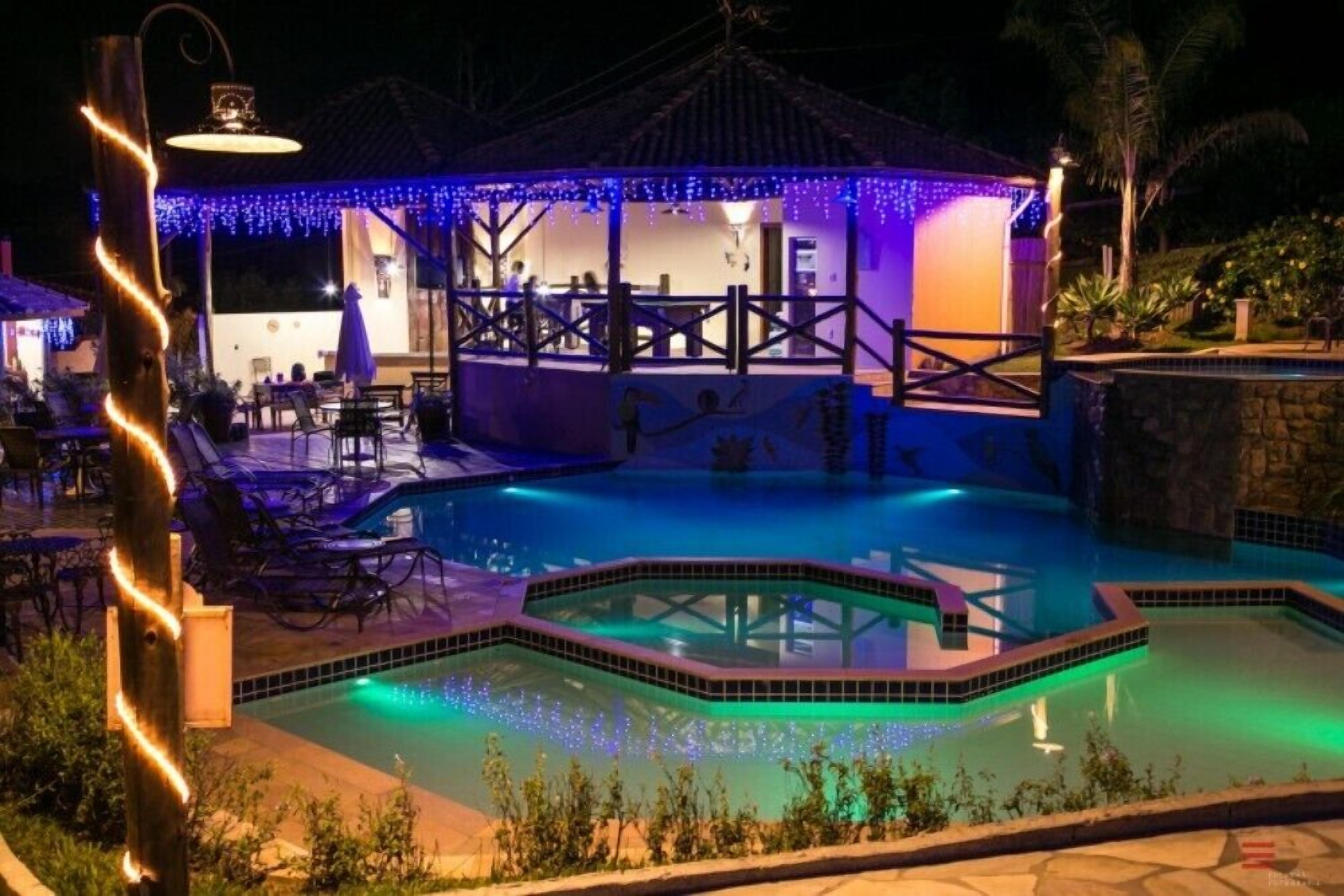 A pool area with a covered seating area, a small pool, and a stone wall.
