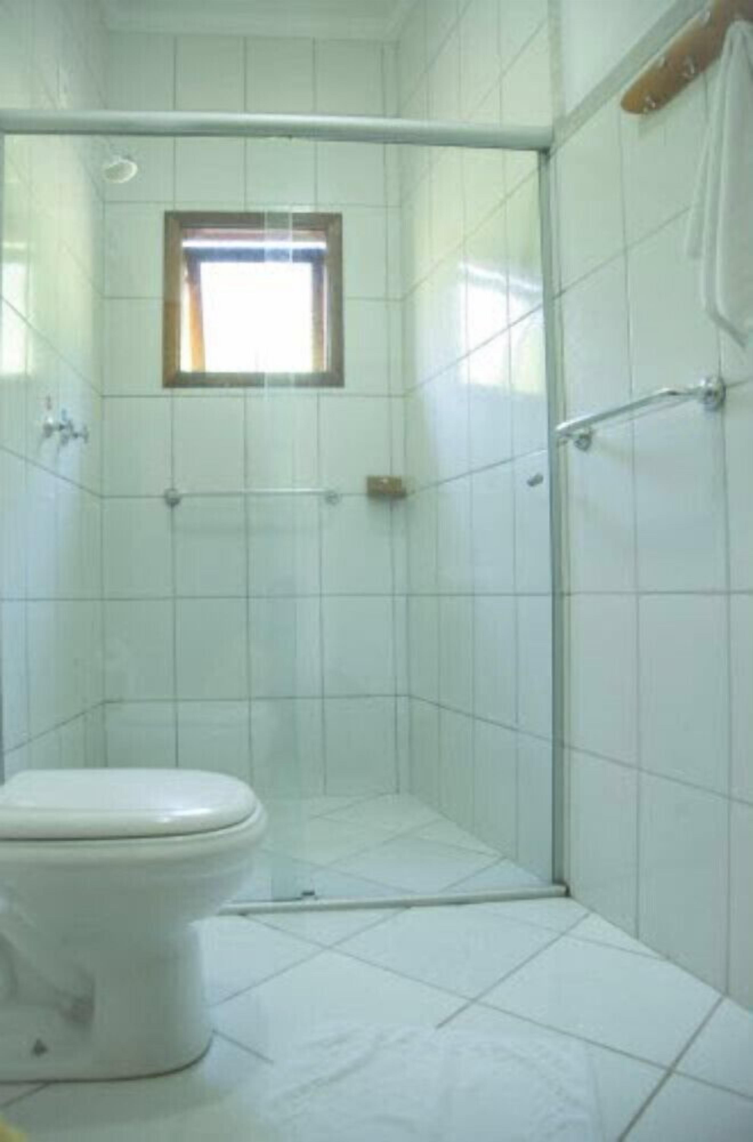 Une salle de bain comprenant des toilettes, un espace douche avec une porte en verre et une petite fenêtre.