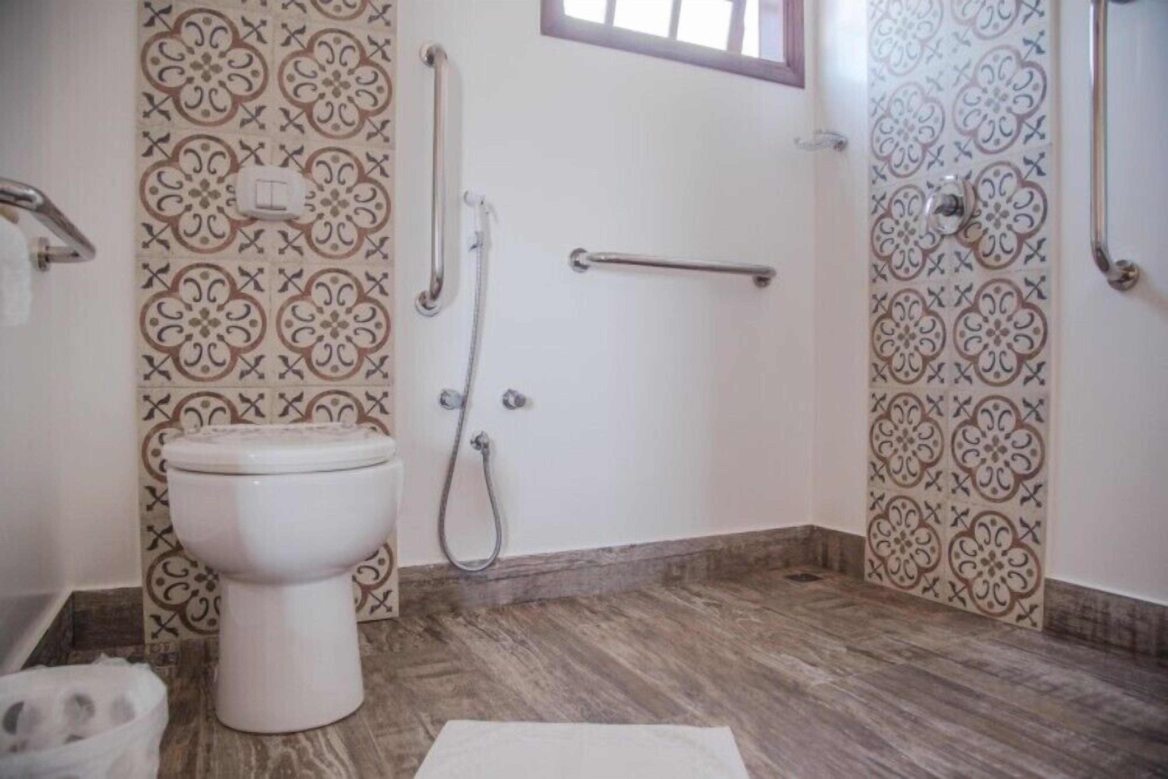 Un baño con inodoro, ducha y barra de apoyo.