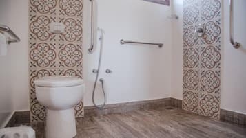 Un baño con inodoro, ducha y barra de apoyo.