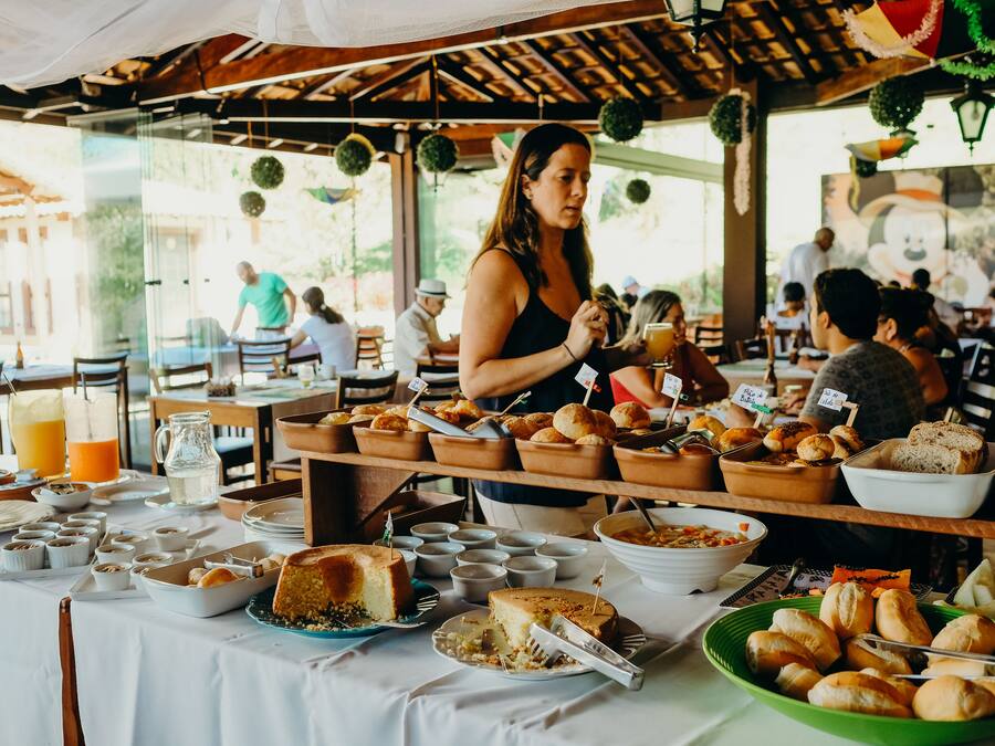 Een buffetopstelling met diverse gerechten en een vrouw die drankjes uitschenkt.