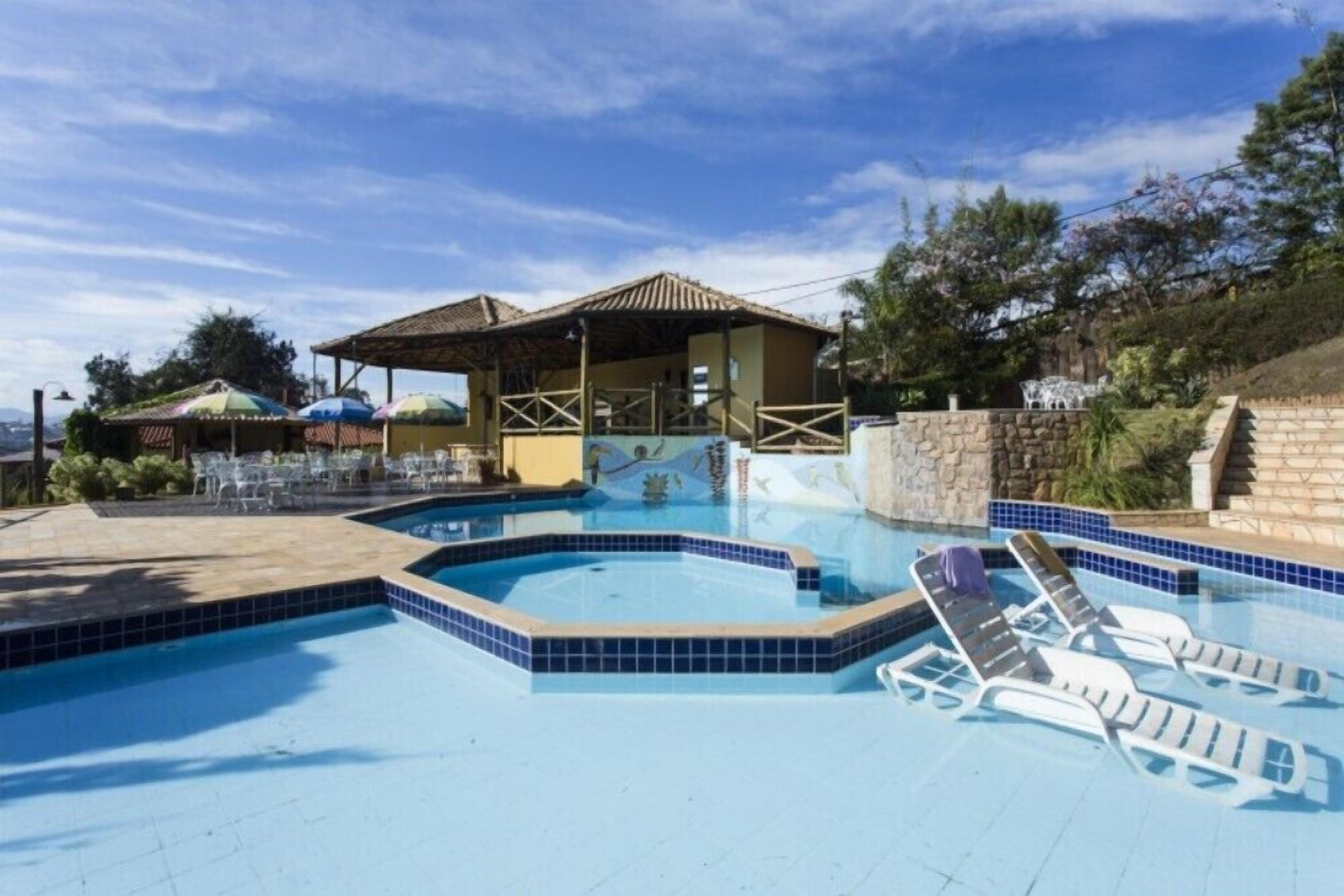 A swimming pool with lounge chairs and a covered seating area.