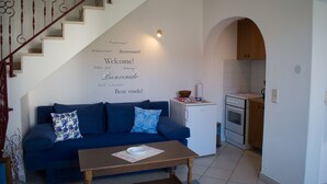 A modern living room with a blue sofa, a wooden coffee table, and a staircase with decorative railings. - Apartmani Exclusive (Rovinj)