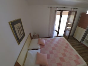Un dormitorio con una cama, una mesita de noche, un cuadro en la pared y una ventana con cortinas.