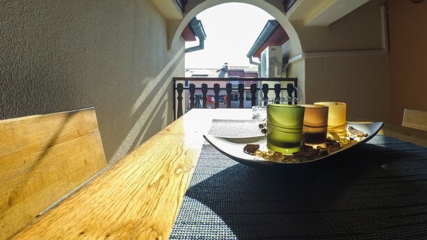 A wooden table with a tray holding a green cup, a glass, and a candle. - Apartmani Exclusive (Rovinj)