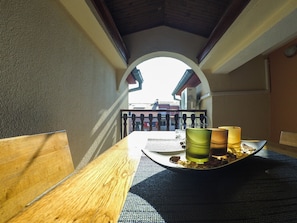 Una mesa de madera con una bandeja que sostiene una taza verde, un vaso y una vela.