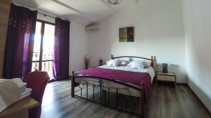 A bedroom with a bed, a chair, a bedside table, and a window with curtains. - Apartmani Exclusive (Rovinj)