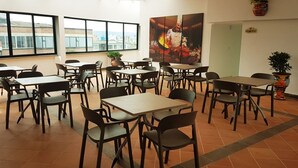 Comedor con mesas y sillas, ventanas amplias y vistas a la ciudad.