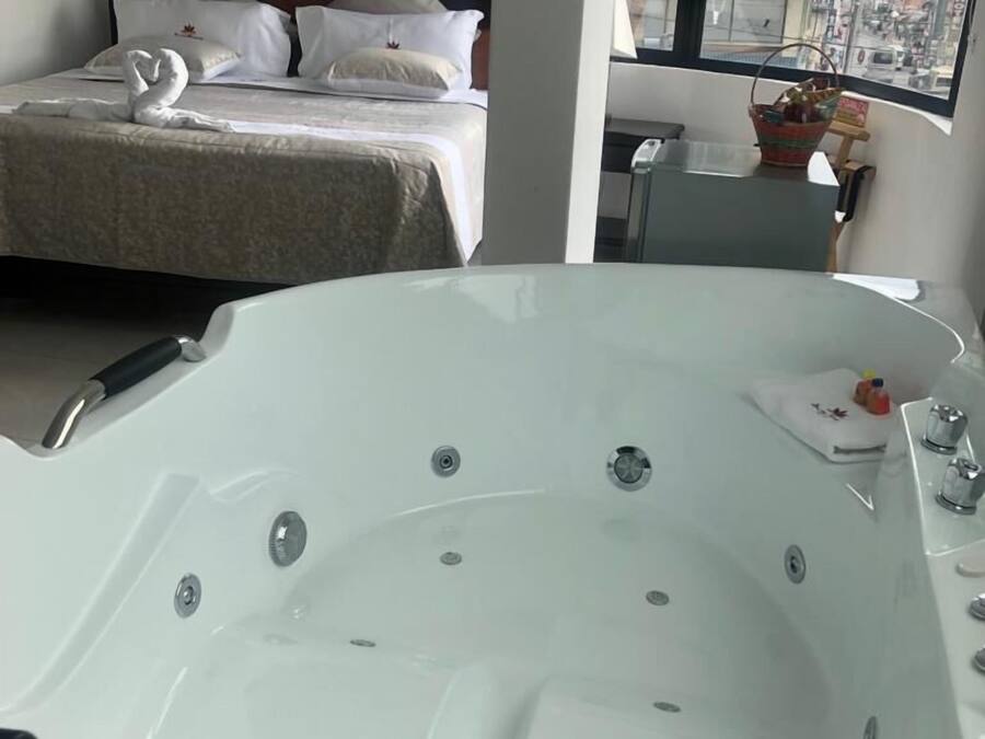 Ein modernes Hotelzimmer mit einer großen Badewanne, einem ordentlich bezogenen Bett und einem Fenster mit Blick auf die Stadt.