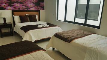 A hotel room with two beds, a nightstand, a window, and a floral wall decoration.