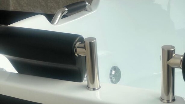 Un baño con un lavamanos moderno y una cama con ropa de cama blanca y almohadas con forma de cisne al fondo.