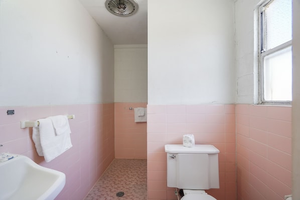 A bathroom with a pink and white color scheme, a white sink, and a toilet.
