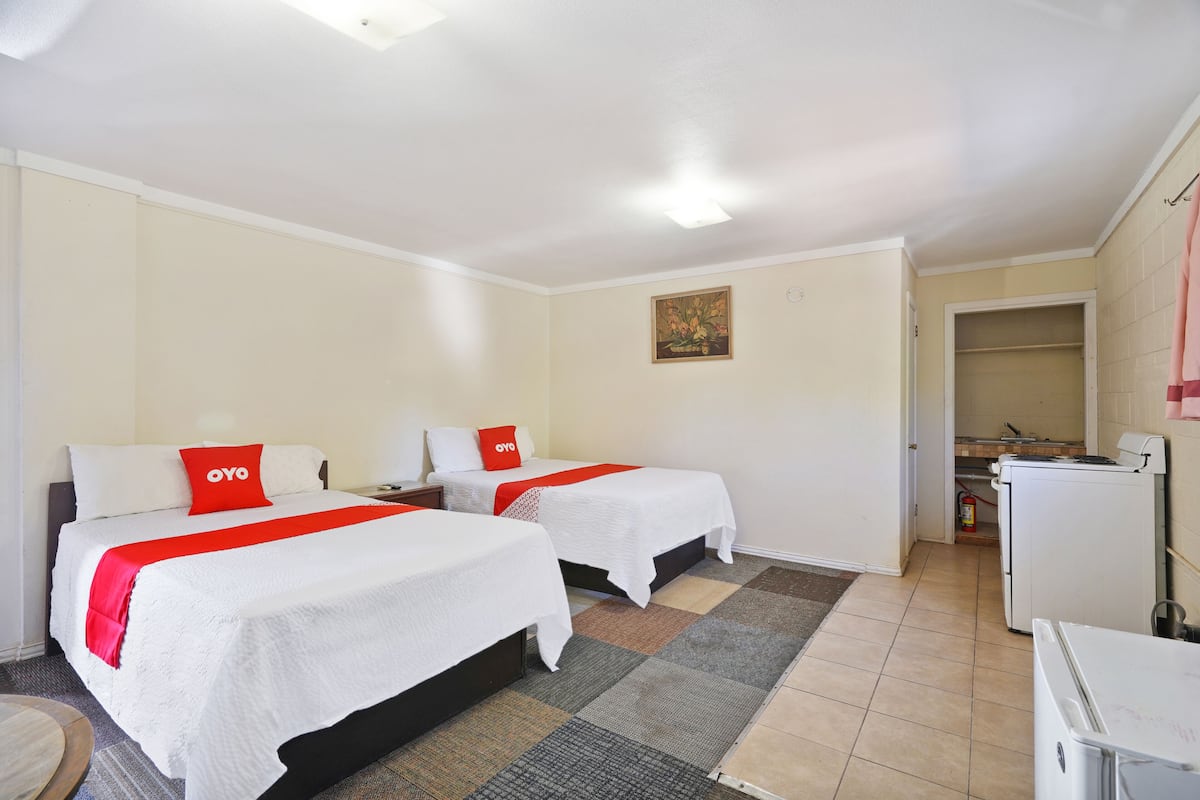 Ein Hotelzimmer mit zwei Betten, einer kleinen Küchenzeile und einem durchgehenden Türbogen sichtbaren Badezimmer.