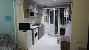 A compact kitchen with a washing machine, a small refrigerator, and a microwave. - Guest House Nise (Tbilisi)
