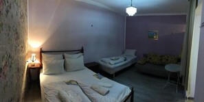A small, dimly lit room with a single bed, a small table, and a sofa. - Guest House Nise (Tbilisi)