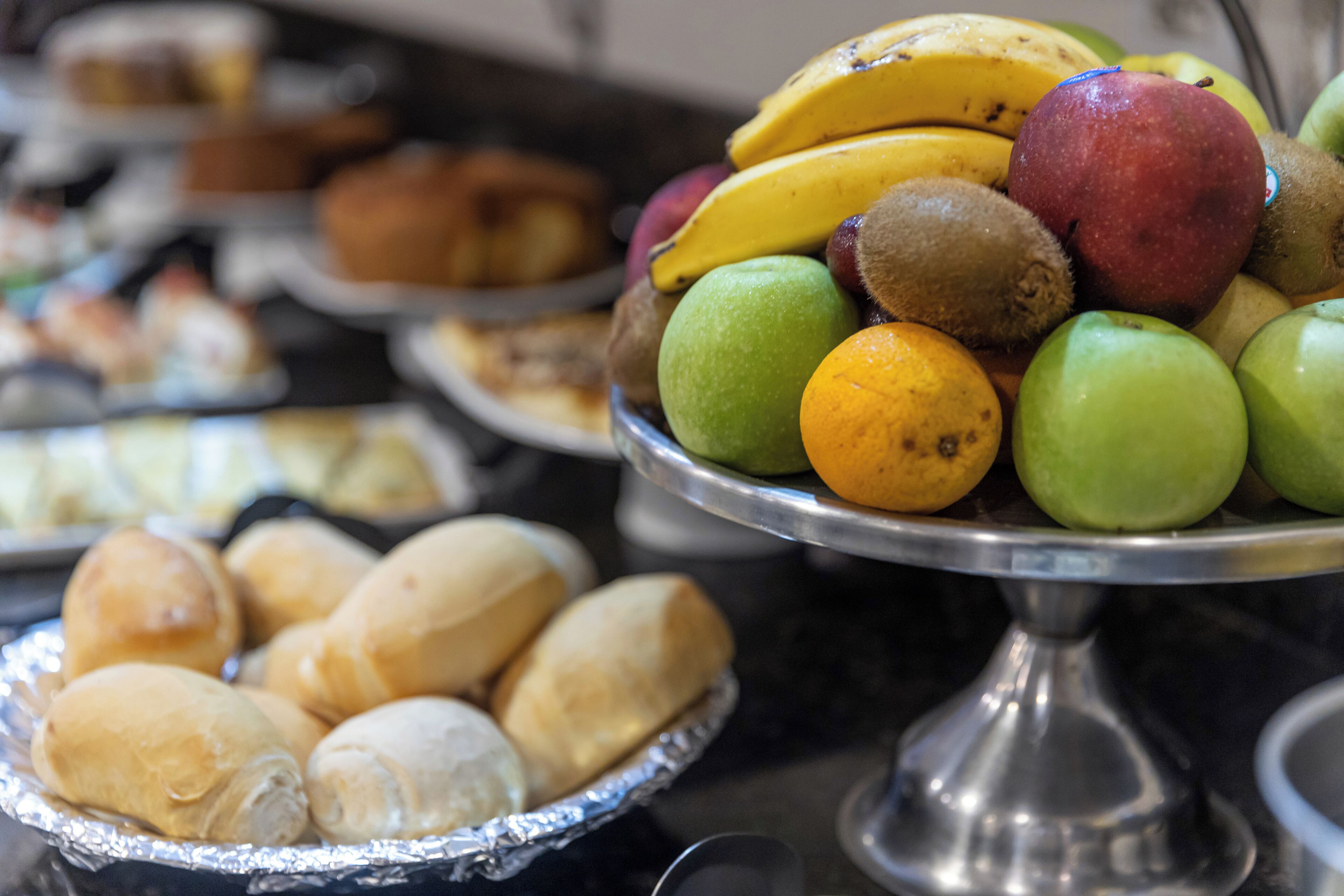 Un buffet con diversi cibi, tra cui frutta, pasticcini e pane.