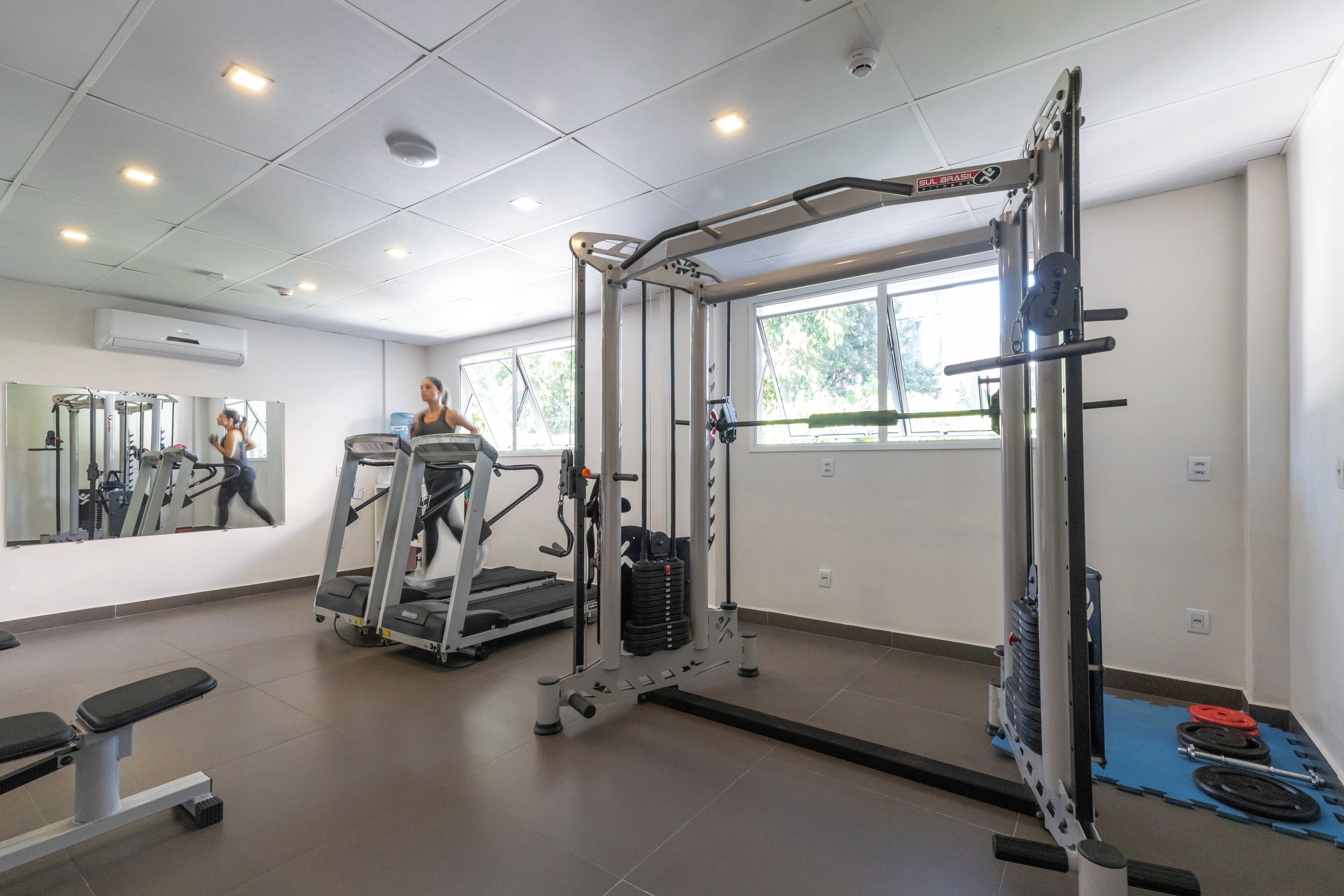 Une salle de sport équipée d’un tapis de course, de matériel de musculation et d’un miroir.
