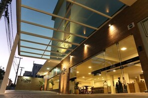 A hotel entrance with a glass facade, a sign indicating a 'Premium' section, and a reception area visible through the glass.
