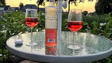A round glass table with two wine glasses and a bottle of wine.