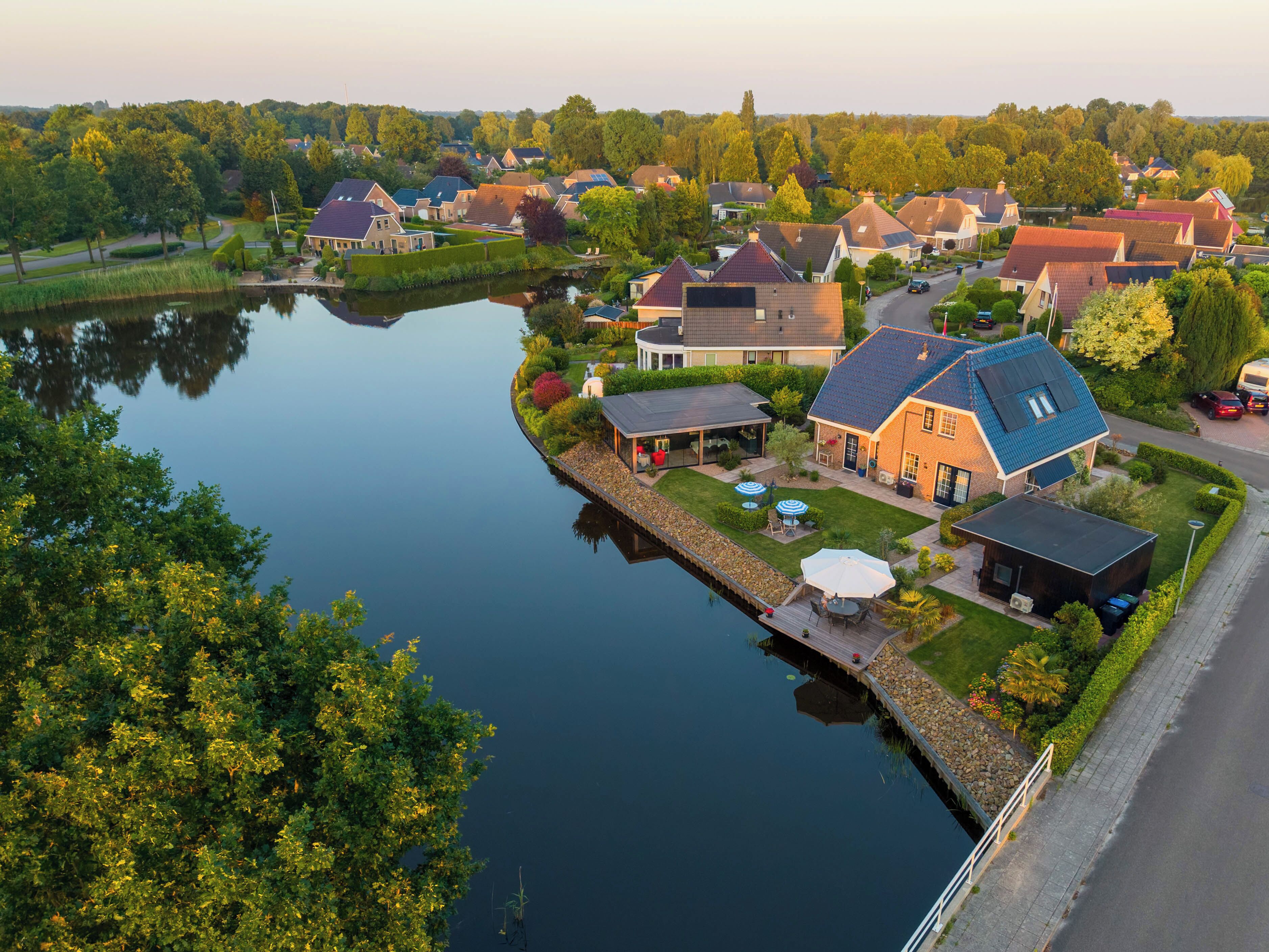 A residential area with houses, a dock, and a calm body of water.