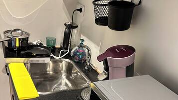 A kitchen with a stainless steel sink, a microwave, and a black countertop.