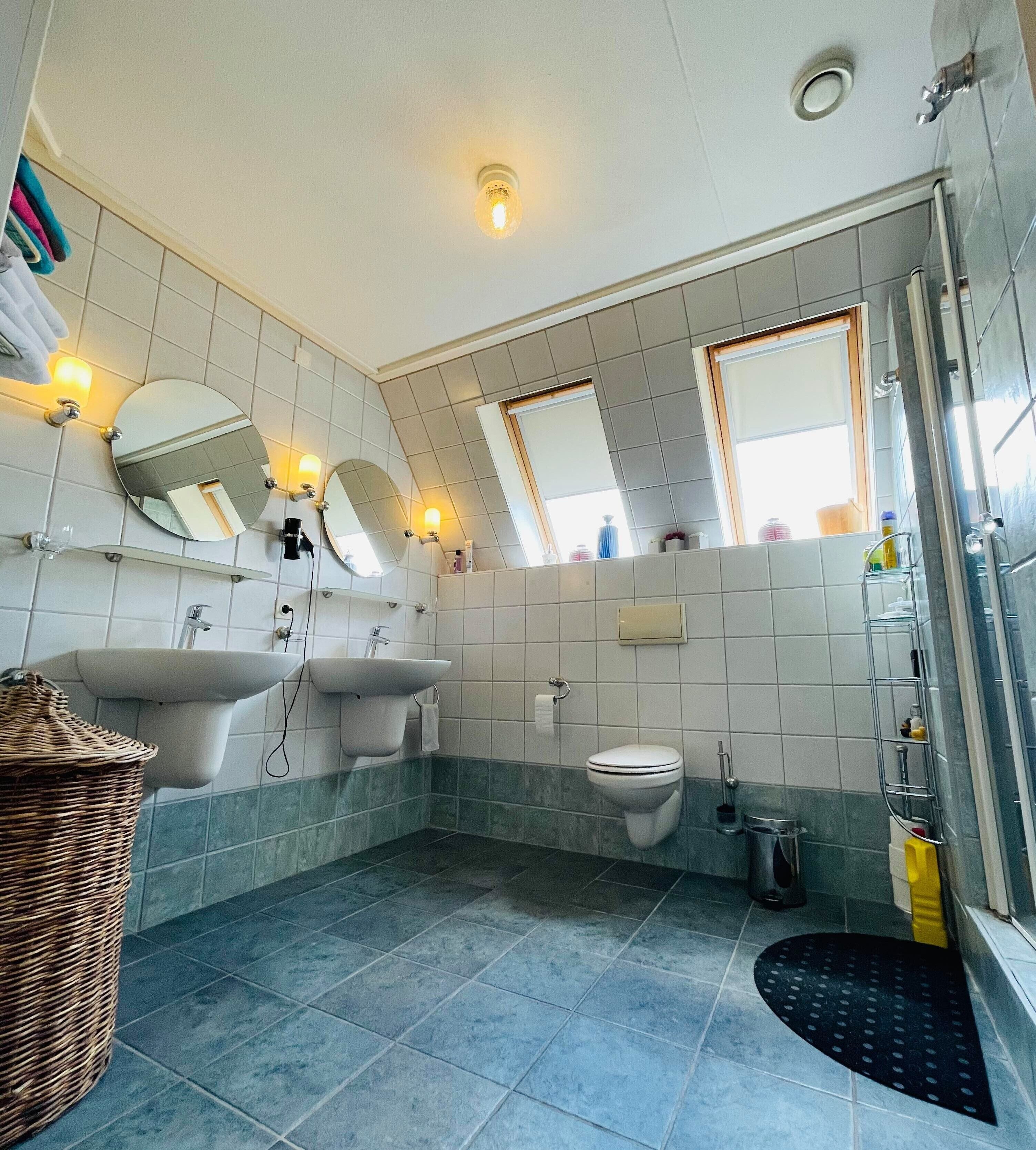 A bathroom with two sinks, a toilet, a shower, and a large mirror.