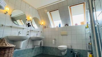 A bathroom with two sinks, a toilet, a shower, and a large mirror.