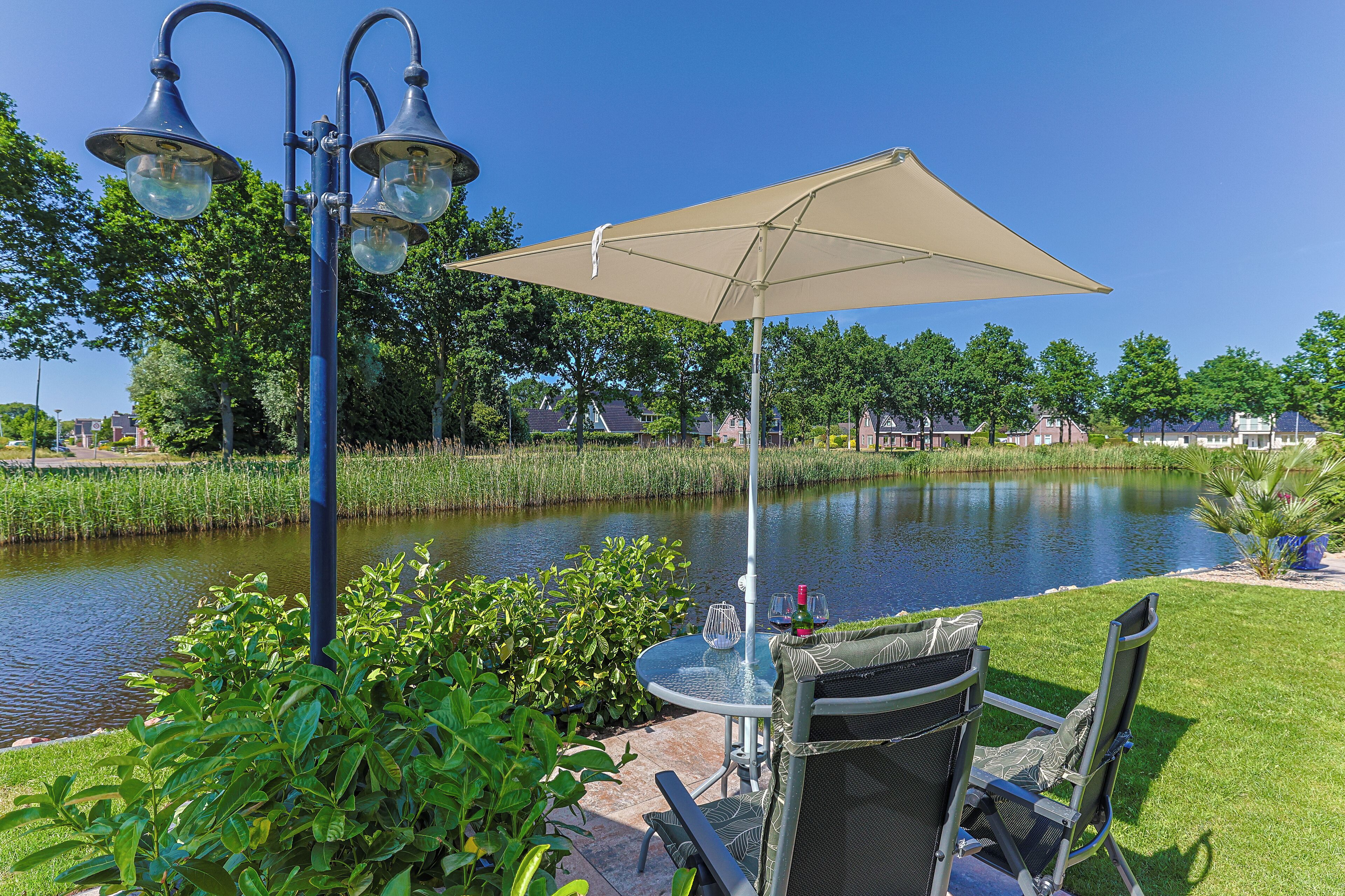 A patio with a table and chairs, a large umbrella, and a lamp post.
