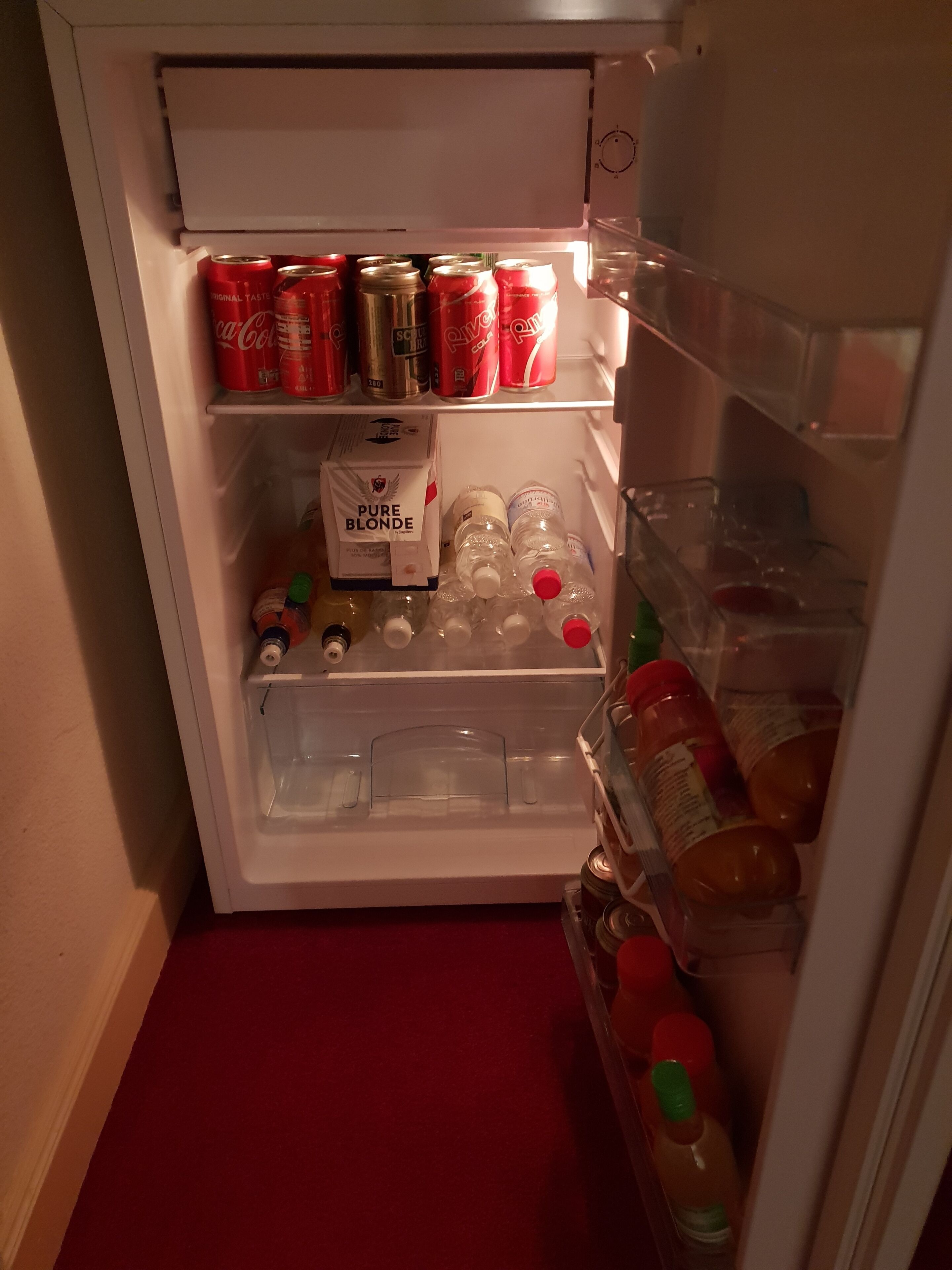 A refrigerator with shelves containing various beverages, including cans and bottles.