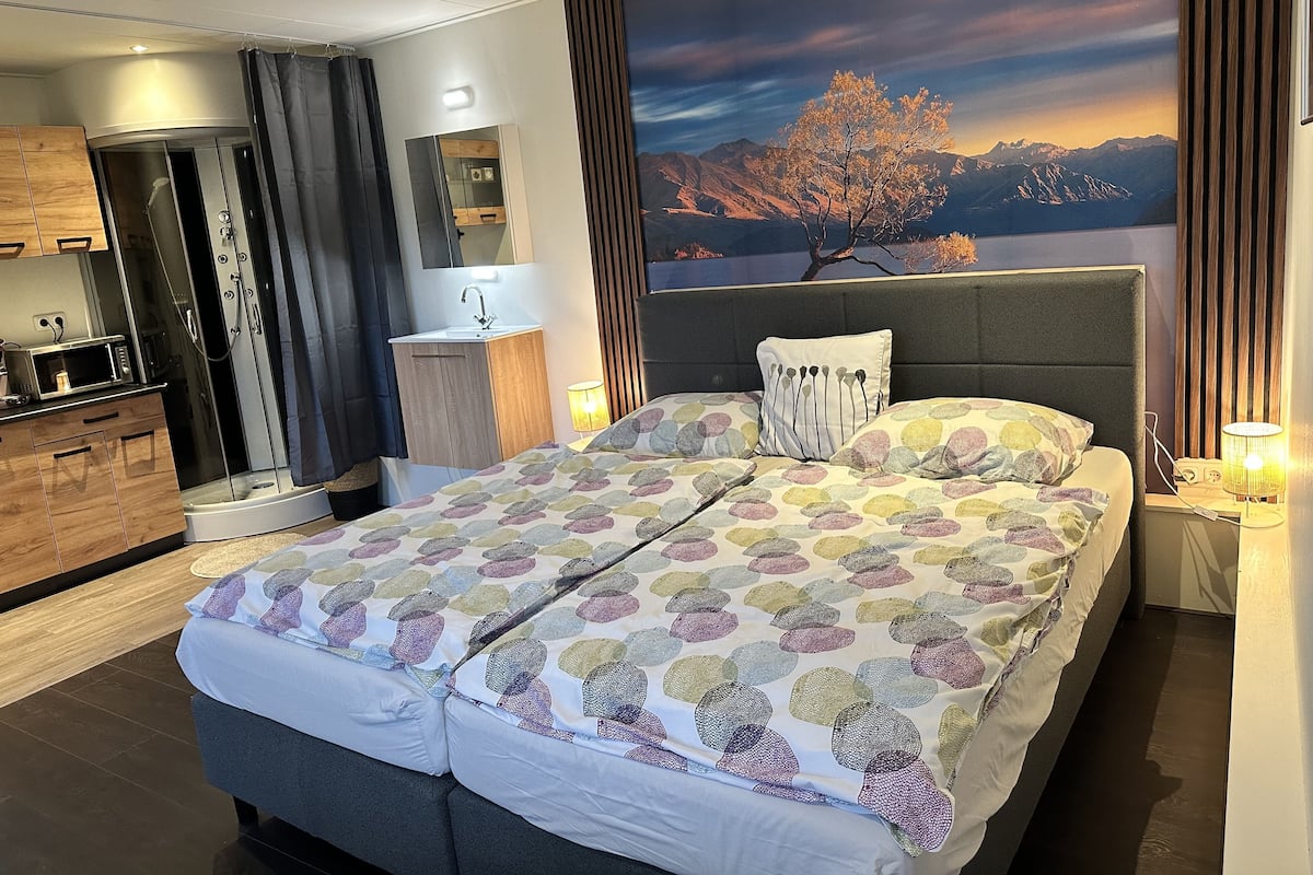 Una habitación de hotel moderna con una cama grande, un baño y una vista panorámica de montañas.
